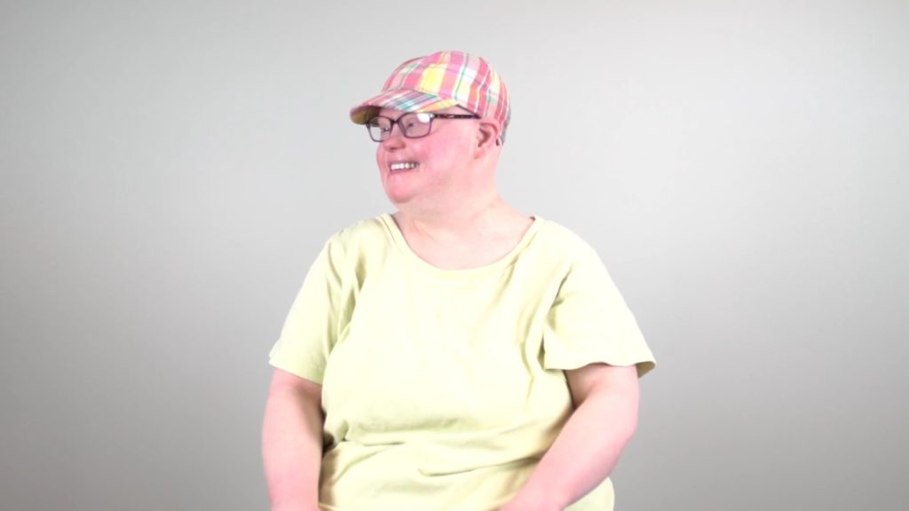 woman with a disability wearing a plaid hat and looking to the right