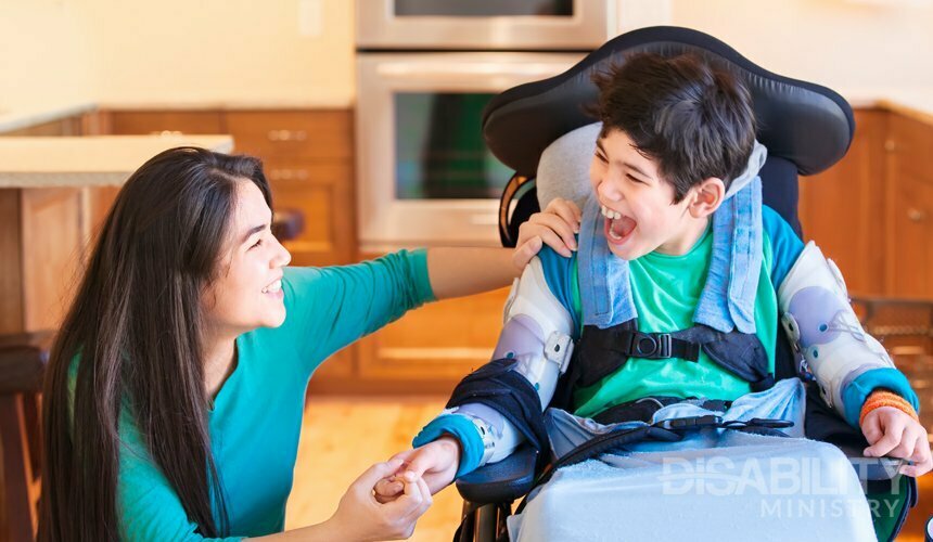 a caregiver with her arm on a boy with a disability