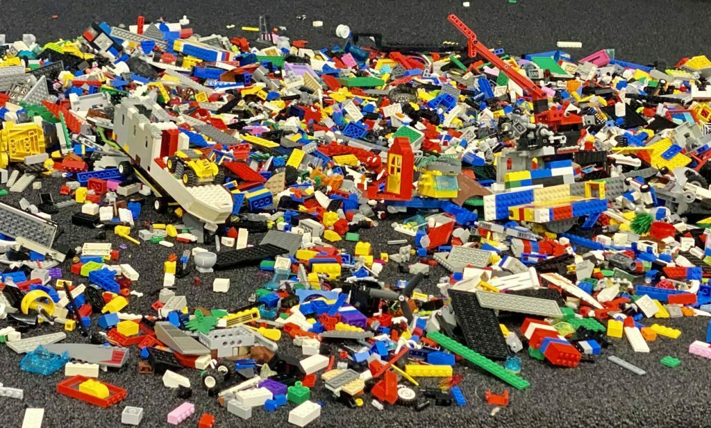 A large collection of Lego bricks spread out on the floor of the classroom.