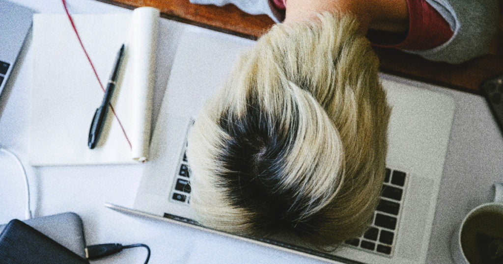 A woman lays her head down on a laptop out of frustration.