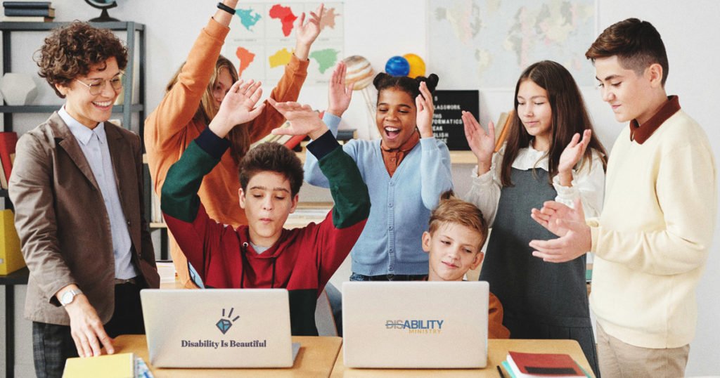 A group of students in a classroom setting looking at a pair of laptops on a desk.