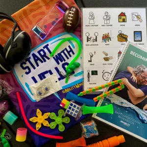 Disability Ministry Starter Kit showing drawstring bag, sensory and fidget items, ear muffs, Baptism Decision workbook, and laminated visual communication card.