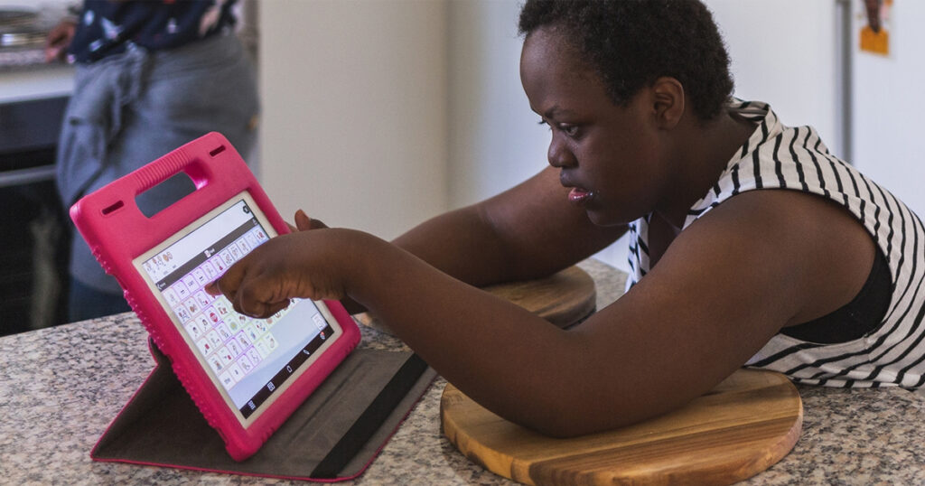 A young African American lady with a disability is using a communication app on a tablet device