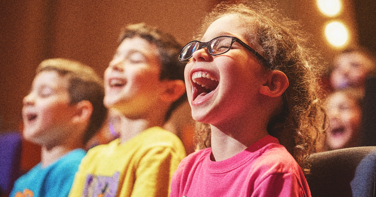 Children seated together at church singing and smiling