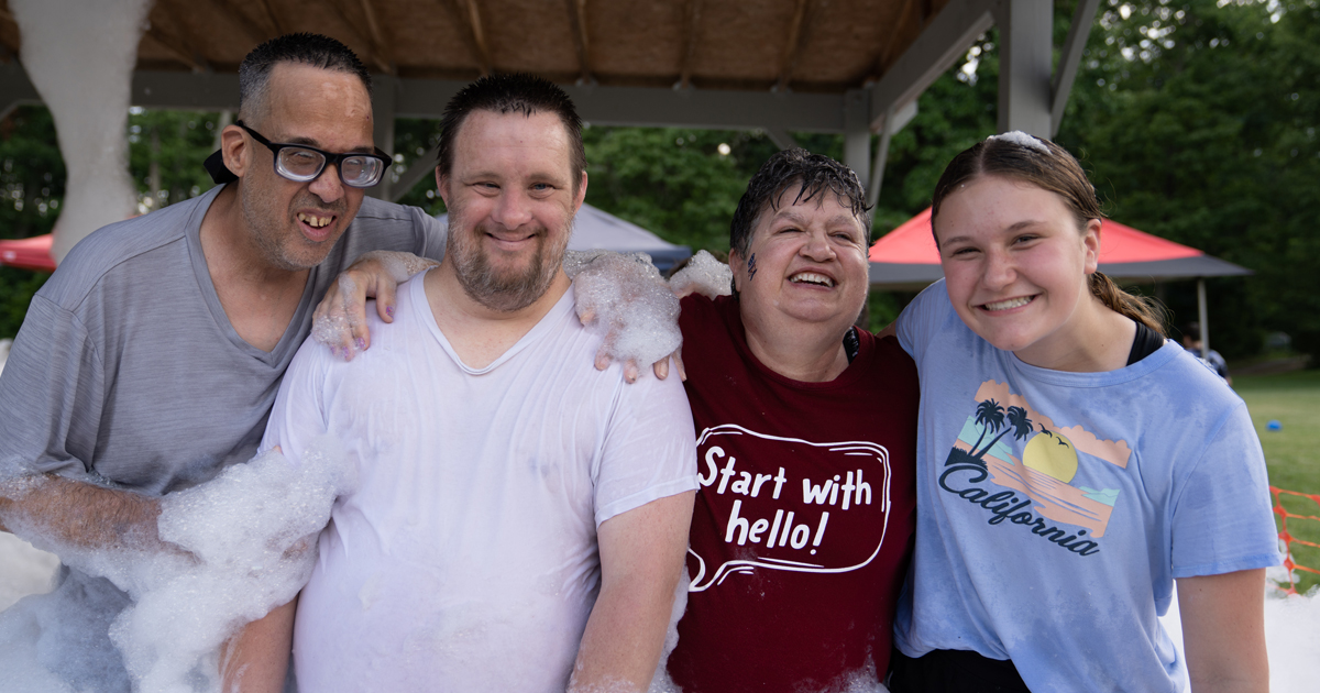 Four individuals having fun outside in a camp-like environment, playing in bubbles