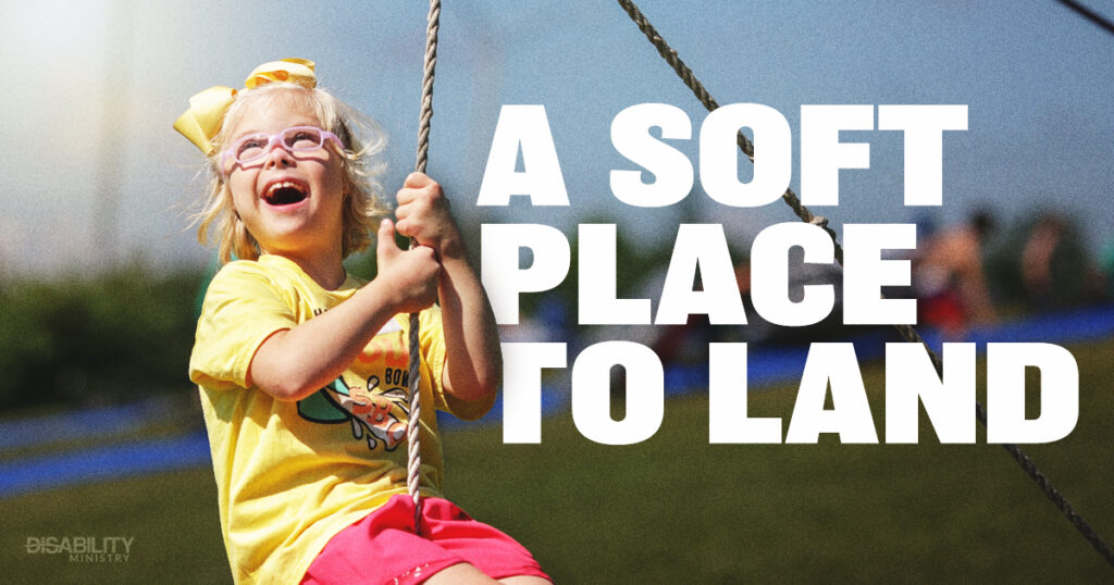Young child wearing glasses and a yellow bow happily swings outside, surrounded by a warm, inviting atmosphere. Large text nearby says A Soft Place to Land, enhancing the sense of comfort in the scene. In the background, blurred figures and green grass suggest an active, lively outdoor setting.