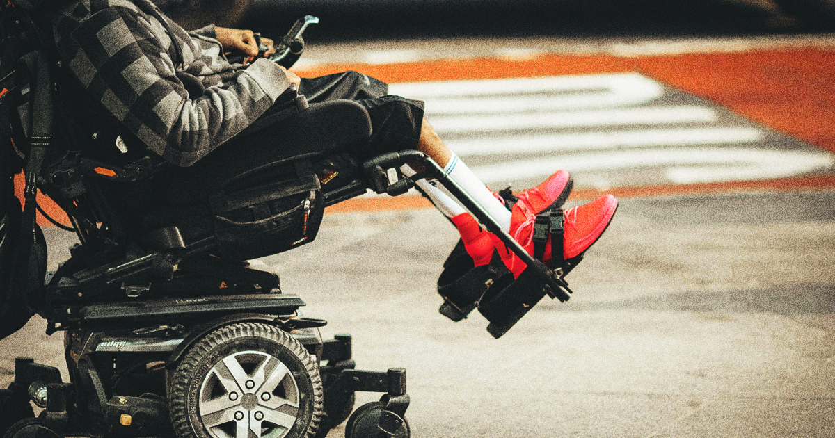A person in a power wheelchair wearing bright red sneakers, representing disability inclusion in the church.